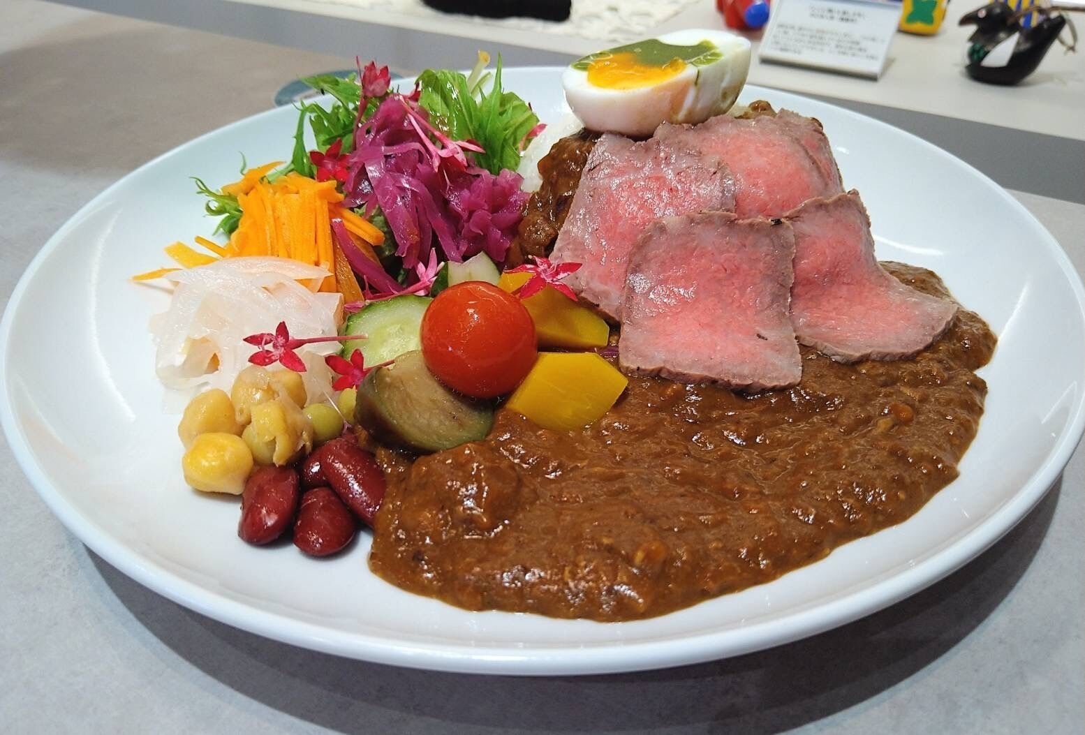 A plate of food with various items including meat, vegetables, and a boiled egg.