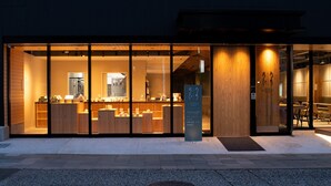 A modern building with a glass storefront, wooden interior, and a signboard outside.