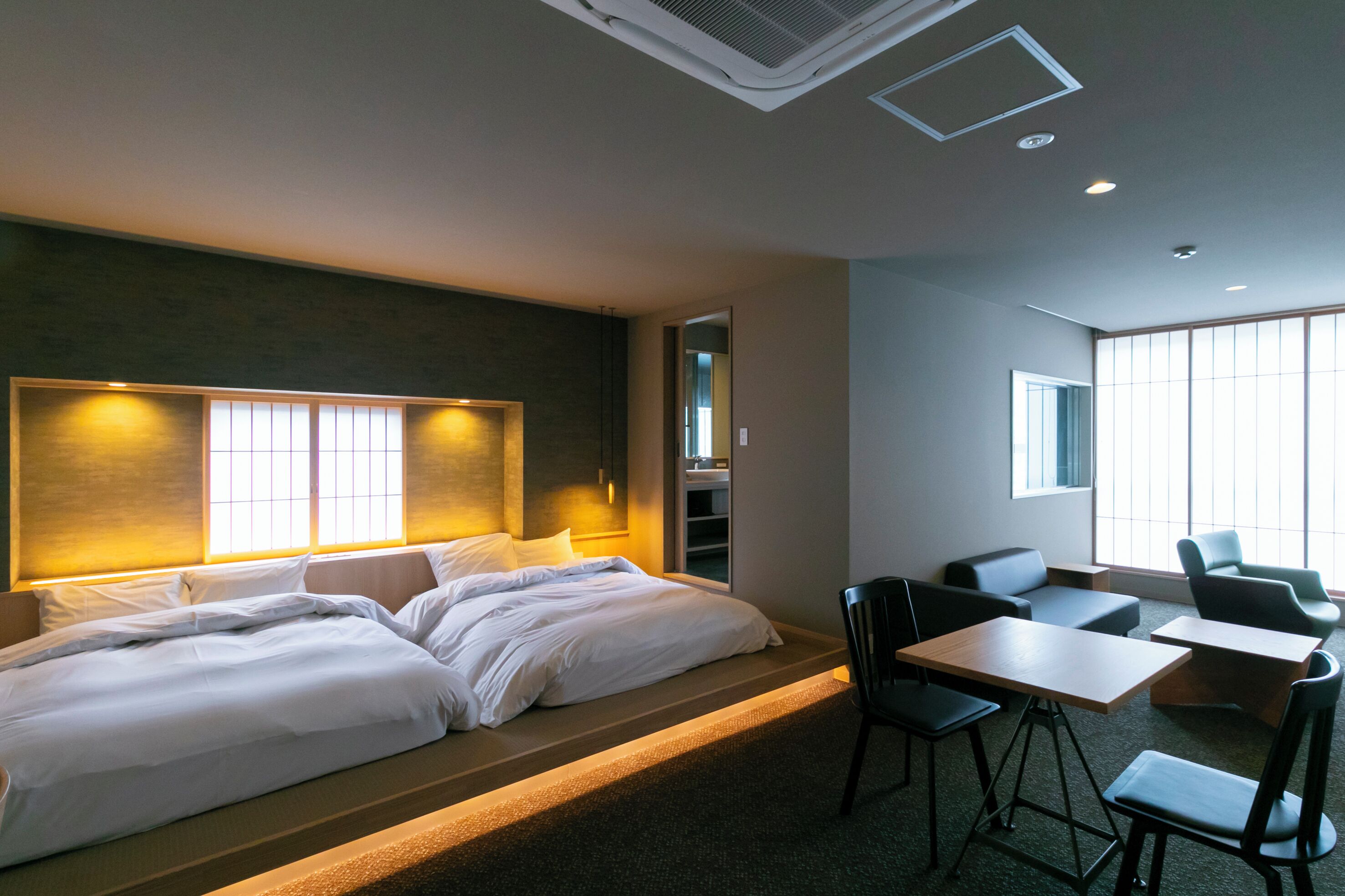A hotel room with a large bed, a desk, and chairs.