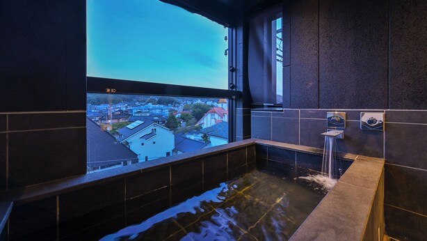 A modern bathroom with a large window, a bathtub, and a shower area.