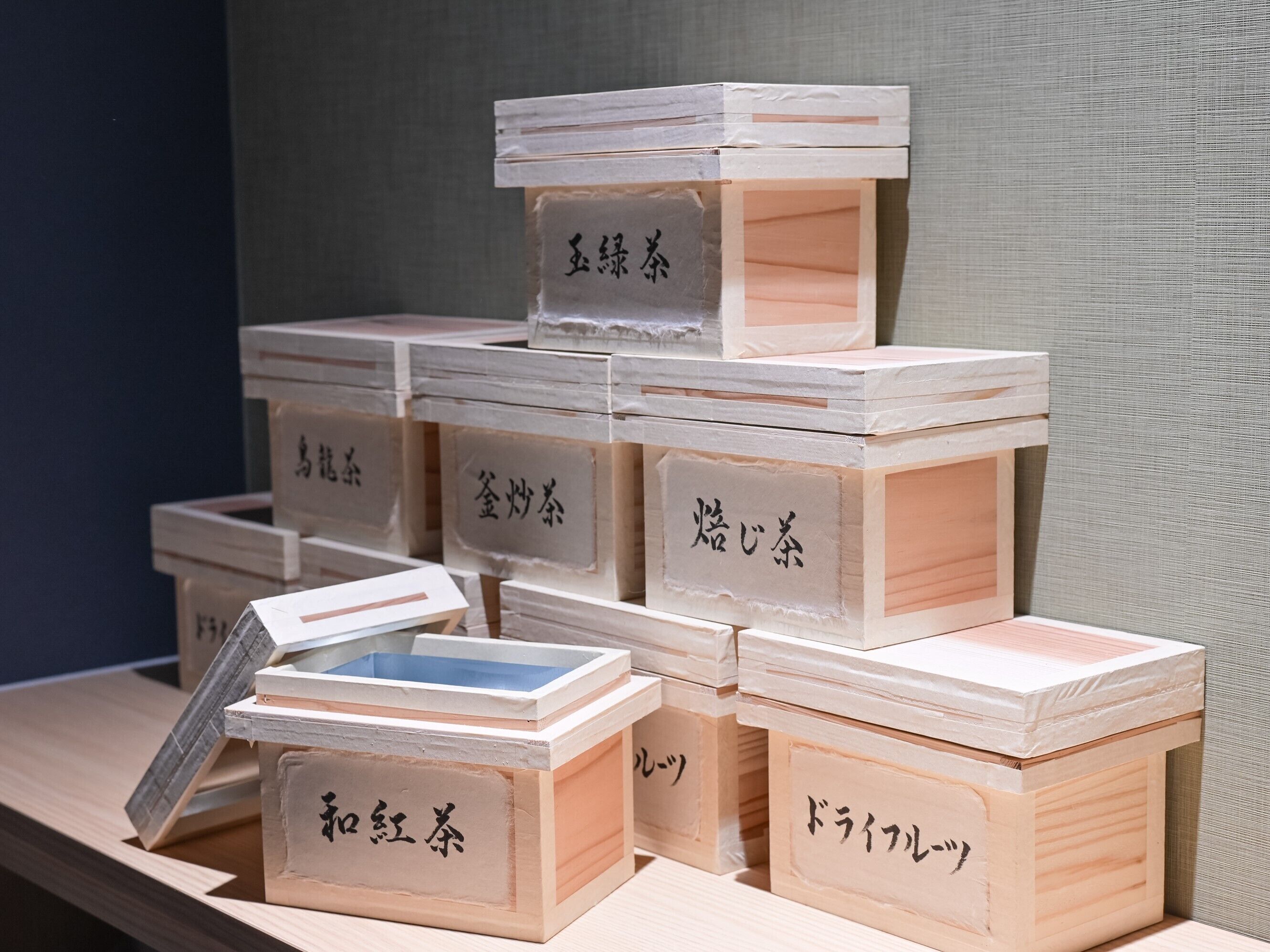 Une présentation de boîtes en bois, chacune portant une étiquette, disposées en une structure pyramidale.