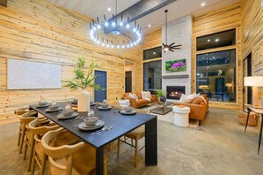 A modern interior with a dining area, a living room with a fireplace, and a large window.