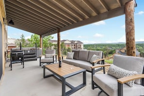 Eine Außenpatio mit Grill, Sitzgelegenheit und Blick auf einen Wohnkomplex.