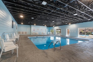 An indoor swimming pool with a clear view of the pool area, including the poolside chairs and the pool's edge.