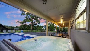 A hot tub with a pool, outdoor seating, and a view of the surrounding area.