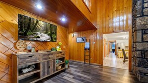 A wooden interior with a TV, a wooden cabinet, and a stone wall.