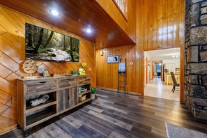 A wooden interior with a TV, a wooden cabinet, and a stone wall.