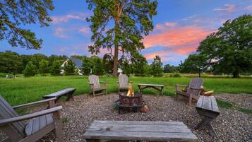 An outdoor seating area with Adirondack chairs, a fire pit, and a picnic table.