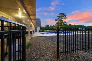A residential property with a swimming pool, outdoor seating, and a view of the sky.