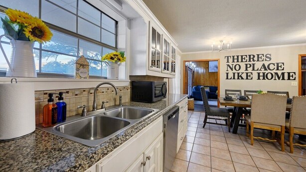 A kitchen with a double sink, a microwave, and a dining area with a table and chairs.