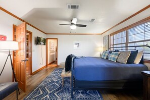 A bedroom with a bed, a desk, a chair, a wardrobe, and a window with blinds.