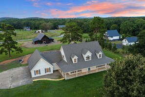 A large house with a spacious front yard and a barn in the background.