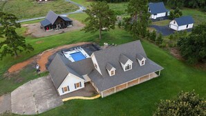 A large house with a swimming pool, multiple attached structures, and a well-maintained lawn.