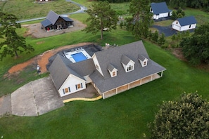 A large house with a swimming pool, multiple attached structures, and a well-maintained lawn.