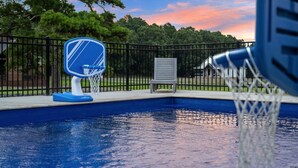 A swimming pool with a basketball hoop and a chair.