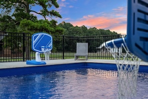 A swimming pool with a basketball hoop and a chair.