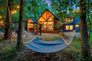 Eine Hütte mit Hängematte, Holzterrasse und Lichterketten.