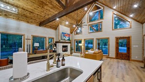 A spacious kitchen with a large island, wooden beams, and large windows. - Hidden Gem · Boho Chic Paradise: Arcade & Fire Pit Swing Area (Broken Bow)