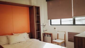 Un dormitorio con cama, un armario de madera, una mesita y una ventana.