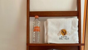 Un estante de madera con una toalla blanca, una botella de agua Bonafont y toallas dobladas.