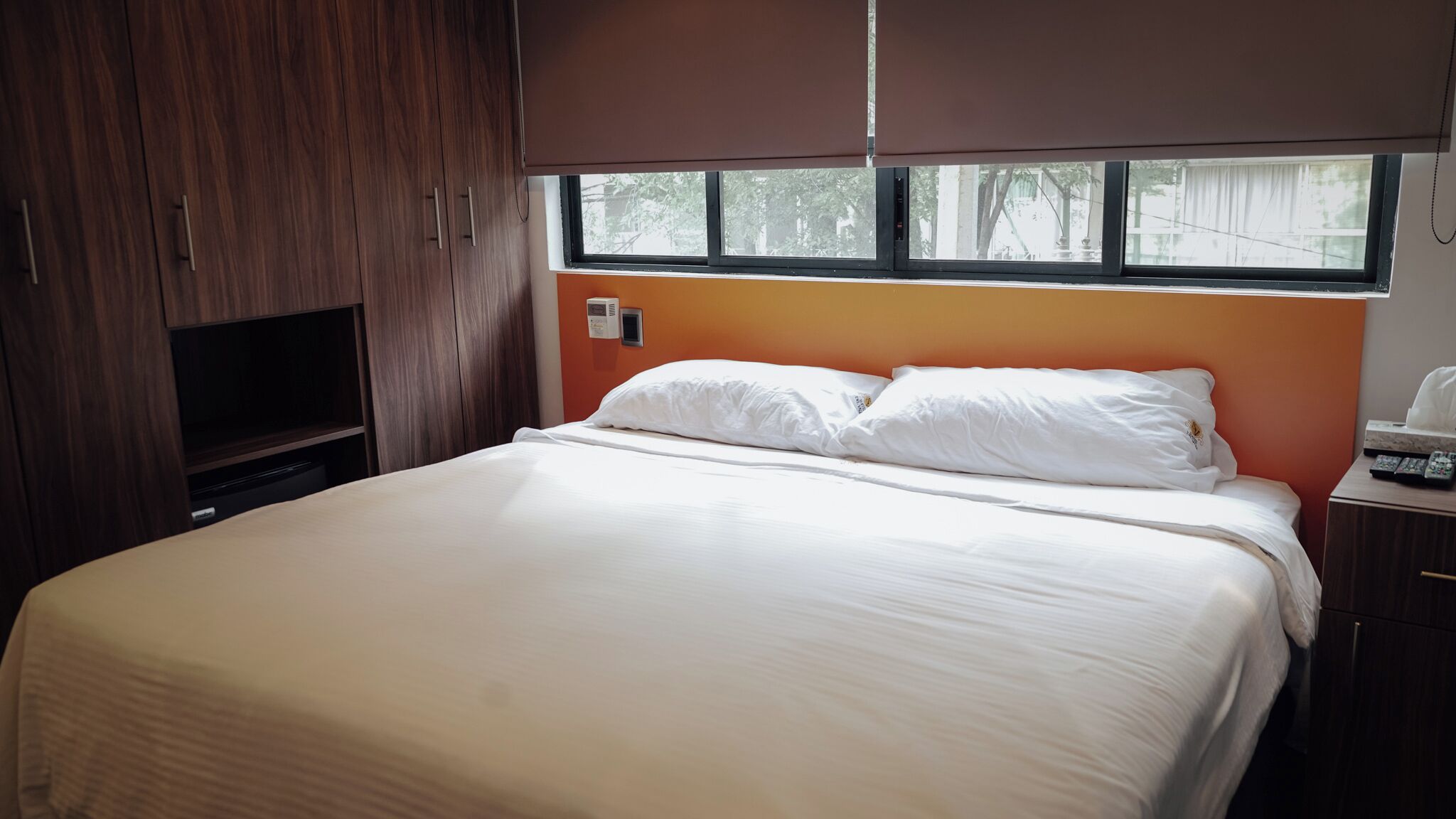 A bedroom with a bed, a TV, and a window.