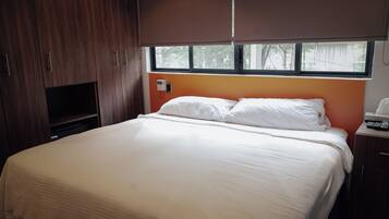 A bedroom with a bed, a TV, and a window.