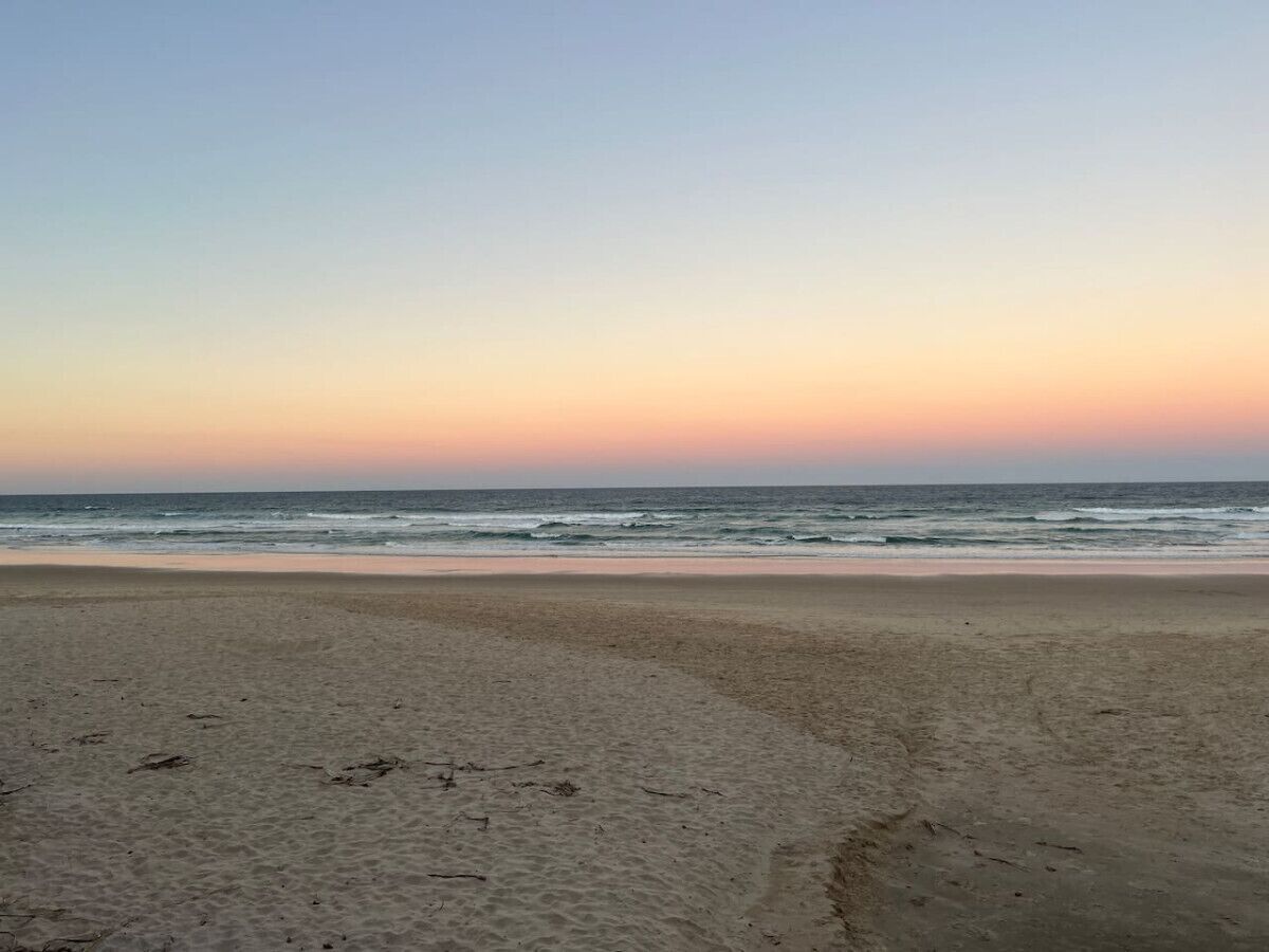 Une plage avec un ciel dégagé et une mer calme.