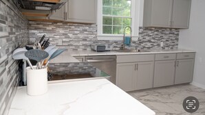 Uma cozinha moderna com painel de azulejos, eletrodomésticos de aço inoxidável e armários em tons claros.