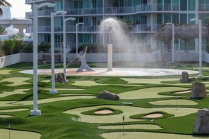 A landscaped garden with a fountain, white columns, and a building with balconies in the background. - Modern 4 Bedroom Condo with Panoramic Views and Large Wraparound Balcony. Complimentary Boat Slip! (Orange Beach)