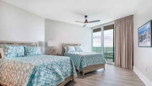 A hotel room with two beds, a ceiling fan, a large window with curtains, and a view of the ocean. - Modern 4 Bedroom Condo with Panoramic Views and Large Wraparound Balcony. Complimentary Boat Slip! (Orange Beach)
