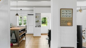 Una cucina moderna con mobili bianchi, un piano di lavoro in legno e vista sul giardino attraverso la finestra.