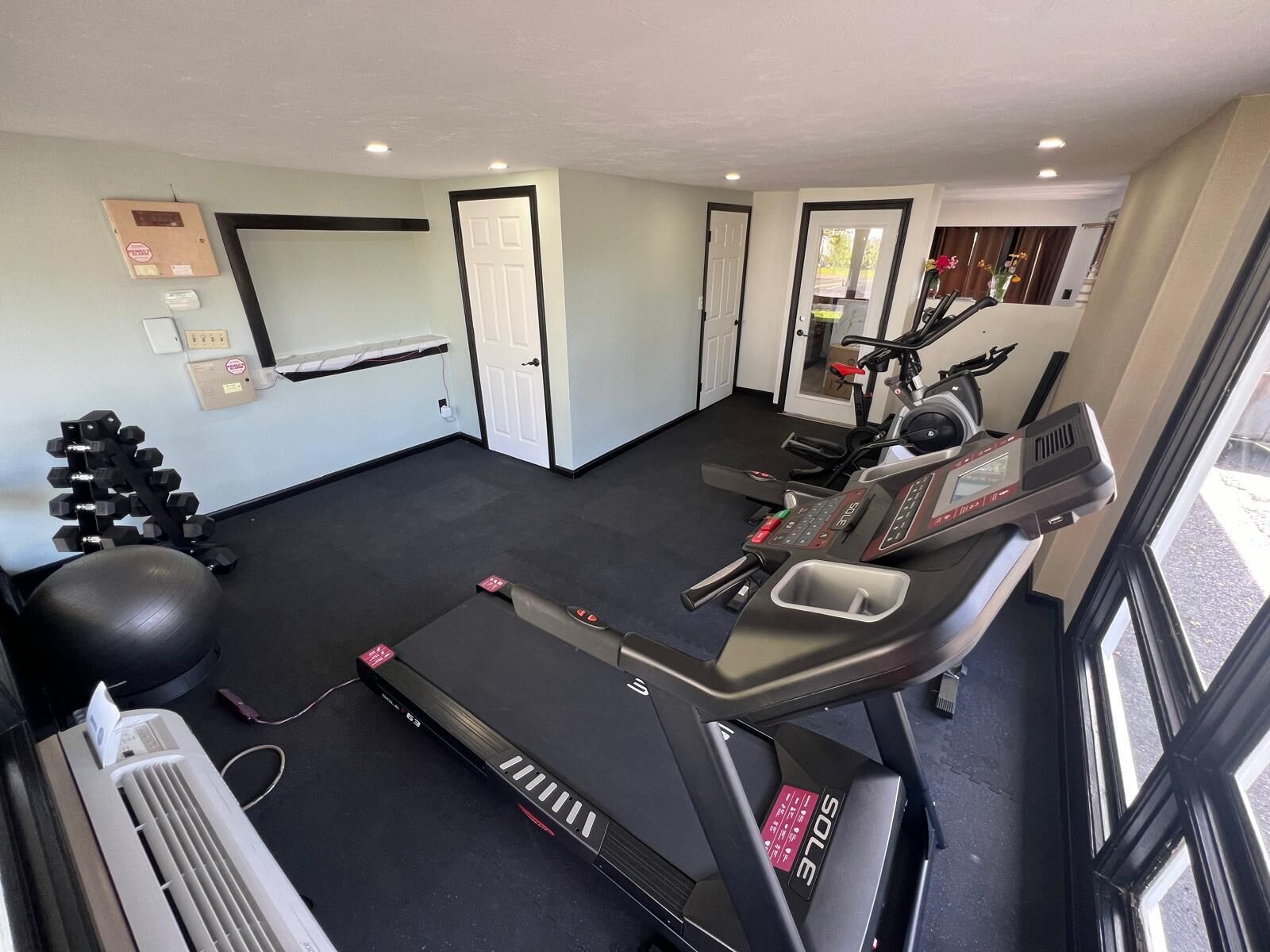 Un gimnasio con cintas de correr, pelotas de ejercicio y mancuernas.
