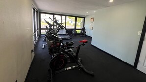 Ein Fitnessstudio mit Trainingsgeräten, großen Fenstern und Ausblick ins Freie.