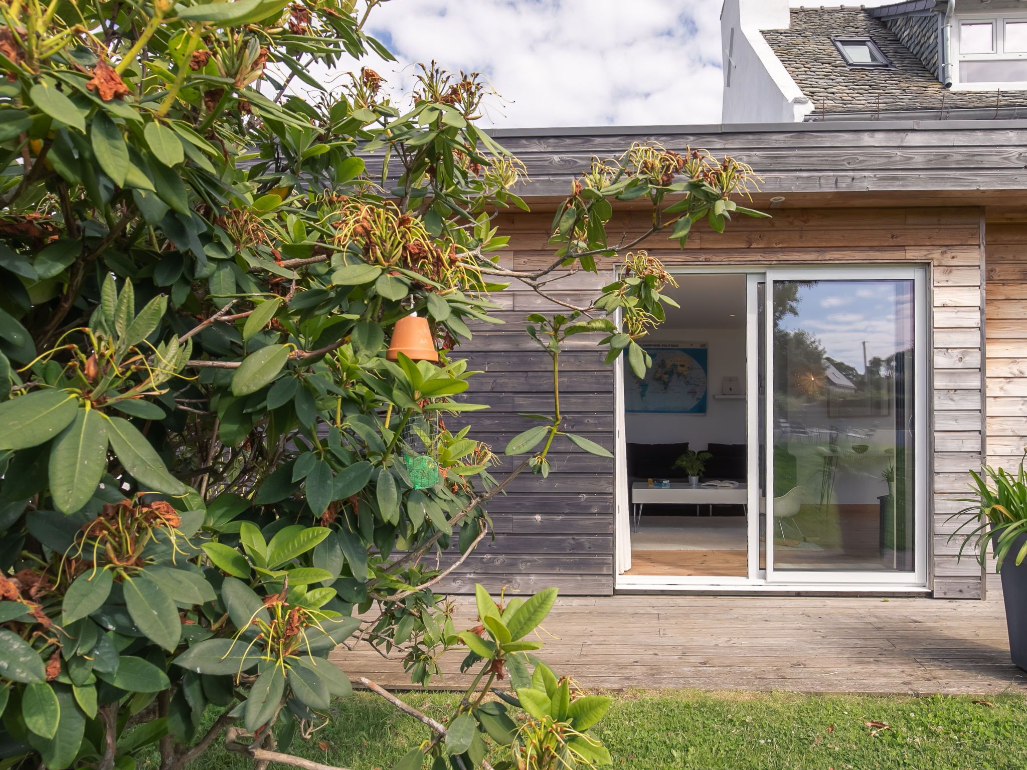 A modern house with a wooden exterior, a glass door, and a visible garden area.