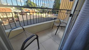 A balcony with two chairs, a metal railing, and a view of a street and buildings. - Próximo a unión medica 2 hab. (Santiago de los Caballeros)