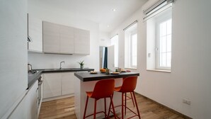 A modern kitchen with a central island, two red bar stools, and a window providing natural light.