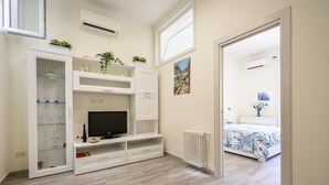 Un dormitorio con cama, televisor, armario blanco y radiador.