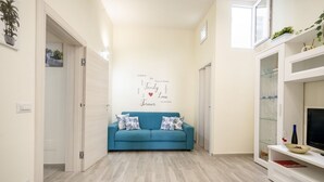 Una sala de estar con un sofá azul, una pared decorada con un collage de palabras y un televisor sobre un pedestal blanco.