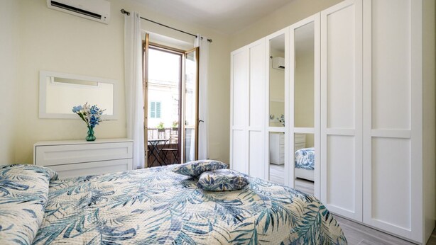 Un dormitorio con cama, cómoda, armario y ventana con vistas.