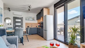 Eine moderne Wohnung mit Essbereich, Küche und einem großen Schiebeglastür zum Balkon.