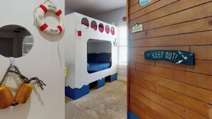 A bunk bed with a "WELCOME" sign, a "KEEP OUT" sign, and a life preserver on the wall. - Elegant home 180 steps from the Beach, 2 King beds, Arcade (Bolivar Peninsula)