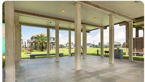 An open covered patio area with concrete flooring and wooden pillars.