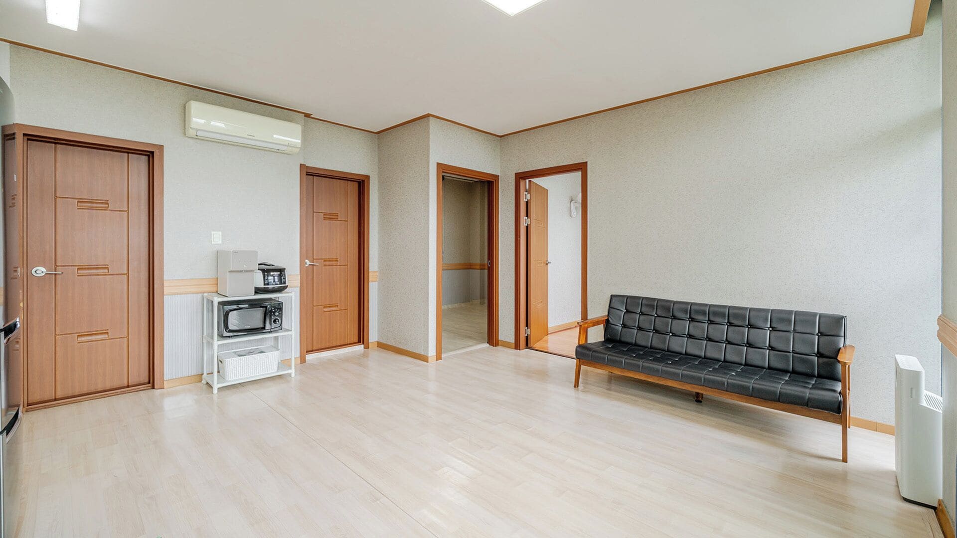 A spacious room with a wooden bench, a microwave, and a wardrobe.