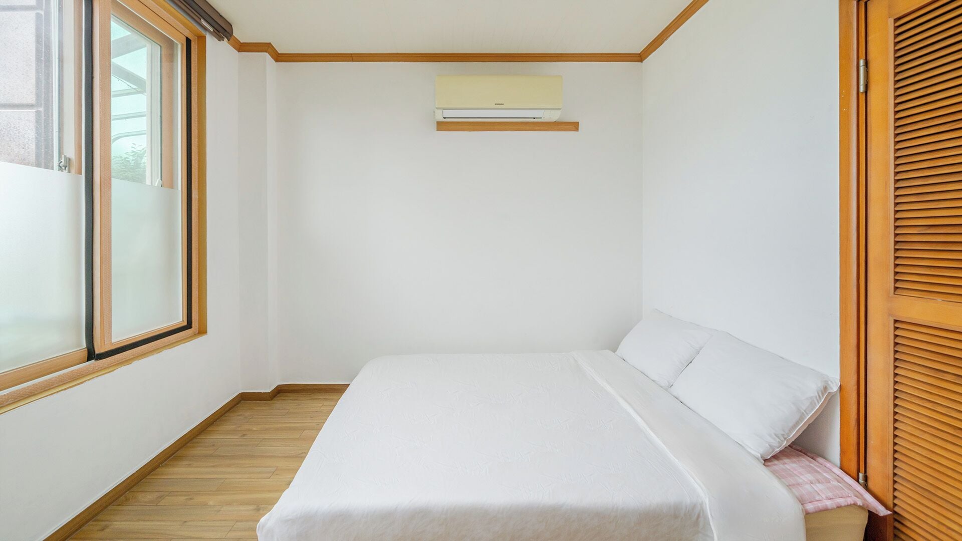 Un dormitorio con cama, ventana y aire acondicionado.