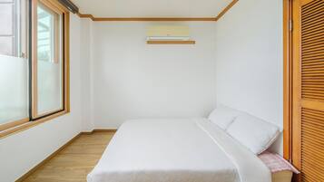 Un dormitorio con cama, ventana y aire acondicionado.