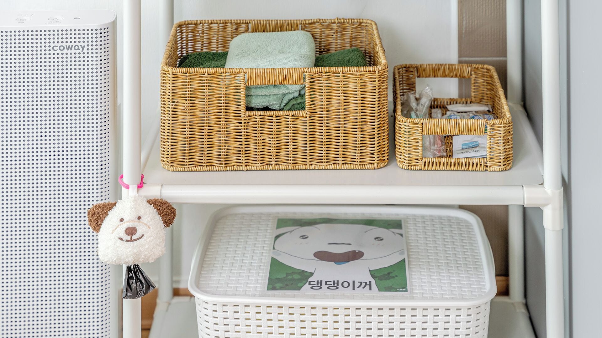 A white shelf with wicker baskets and a white laundry basket with a cartoon character design.