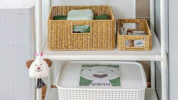 A white shelf with wicker baskets and a white laundry basket with a cartoon character design.