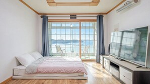 A bedroom with a bed, a TV, and a view of the sea.