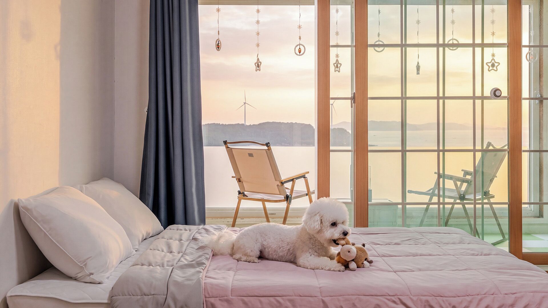 A bedroom with a bed, a chair, and a view of the sea.