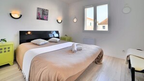 A bedroom with a large bed, two bedside tables, a window, and wall-mounted lighting.